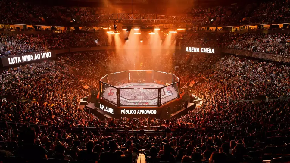 Arena UFC com octógono iluminado durante evento ao vivo em 2026